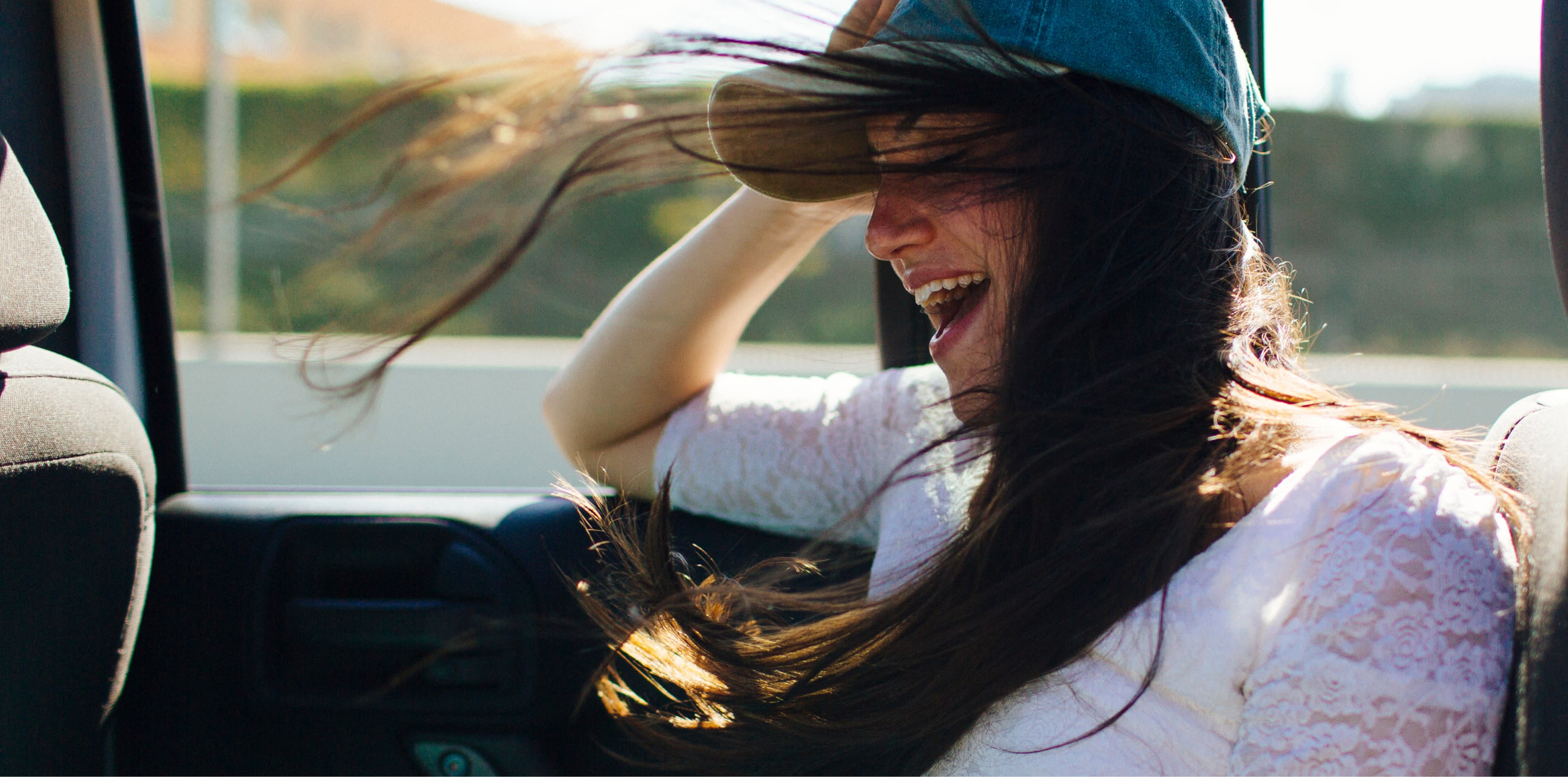 Girl in the backseat of a car, caught in a joyous moment as the mind blows through her long brown hair.